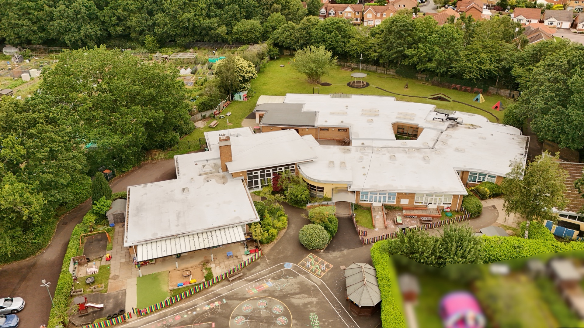 Top-down drone aerial of a nursery school's grounds, playground and allotments