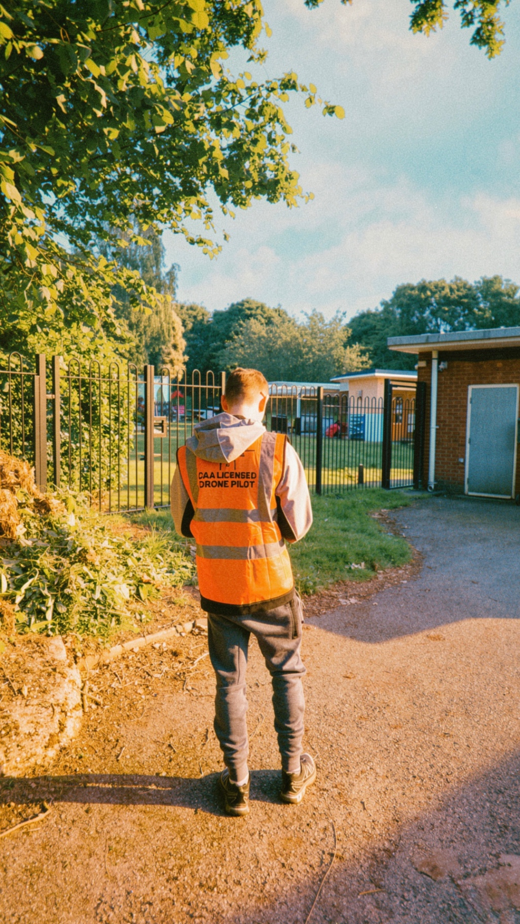 CAA-licensed drone pilot on site at golden hour, hi-vis vest